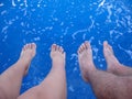 Female and male feet above the blue sea water, summer