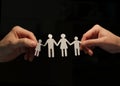 A female and a male hand holding a paper family by the hand. Royalty Free Stock Photo