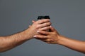 Female and male hand mock paper cup with tea or coffee drink, on isolate gray background. Gray background, copy space