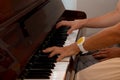 female and male hands, a girl with a guy playing the piano, fingers close-up, horizontal image Royalty Free Stock Photo