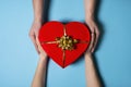 Female and male hands holding Red Heart shaped gift box with gold bow over blue background. Top view. Valentine`s Day, birthday, Royalty Free Stock Photo