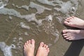 Female and male legs with huge sparkling snowflake on the sand in the sea foam.