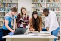 Female and male multiethnic students study in the college library. Learning and preparing for exam. Education concept. Royalty Free Stock Photo