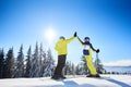 Female and male skiers high five to each other under sunny blue sky. Successful skiing up to mountain top. Full-length.