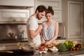 Female and male vegeterians stand together against kitchen interior, prepare vegetable salad. Family couple cook on cozy