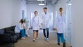 Female and man doctors walking through the modern corridor in the hospital some other nurses and doctor on the chair Royalty Free Stock Photo