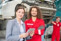 Female manager and car mechanic while working in auto repair shop, Young woman client at car garage getting mechanical service, Royalty Free Stock Photo