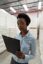 Female manager with headset and clipboard looking at camera in warehouse Royalty Free Stock Photo