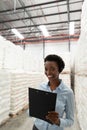 Female manager with headset and clipboard looking at camera in warehouse Royalty Free Stock Photo