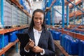 Female manager looking at camera while holding clipboard in warehouse Royalty Free Stock Photo