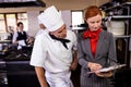 Female manager and male chef writing on clipboard in kitchen Royalty Free Stock Photo