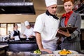 Female manager and male chef writing on clipboard in kitchen Royalty Free Stock Photo