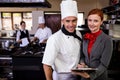 Female manager and male chef writing on clipboard in kitchen Royalty Free Stock Photo