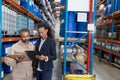 Female manager and male worker discussing over clipboard in warehouse Royalty Free Stock Photo