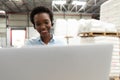 Female manager talking on headset while using laptop at desk in warehouse Royalty Free Stock Photo