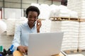 Female manager talking on headset while using laptop at desk in warehouse Royalty Free Stock Photo