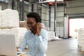 Female manager talking on headset while using laptop at desk in warehouse Royalty Free Stock Photo