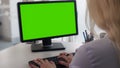 Female manager typing documents on personal computer with green screen, backview