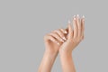 Manicure female hand with gel polish white long nails and red hearts desing on a gray background Royalty Free Stock Photo