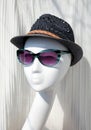 Female mannequin head wearing blue women sunglasses and a wicker hat on sale in a boutique window Royalty Free Stock Photo