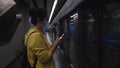 Female with mask using smartphone while waiting for subway train amid coronavirus pandemic