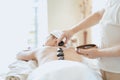 Female massage therapist giving a massage at a spa. Woman having hot stones on her back in spa salon Royalty Free Stock Photo