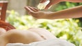 Massage therapist pouring essential oil for massage at spa