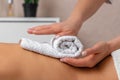Female masseur hands putting white towel on the back of young woman enjoying treatment procedure in spa salon, atmosphere of calm