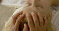 Female masseur is kneading forehead of young woman patient, closeup of fingers, rejuvenating
