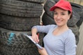 Female mecanic surrounded by stacks car tyres