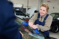 Female mechanic changing windscreen on car