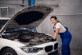 A female mechanic inspects the engine of a car