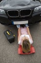 Female mechanic on a crawler to access underside of a automobile.