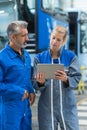 female mechanic looking at tablet with senior male colleague