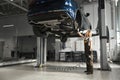 Female mechanic observing undercarriage of lifted car. Royalty Free Stock Photo