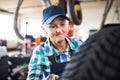 Senior female mechanic repairing a car in a garage. Royalty Free Stock Photo