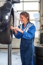 Female mechanic replacing vehicle tyres