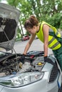 female mechanic in uniform trying to repair auto which broke down Royalty Free Stock Photo