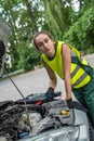 female mechanic in uniform trying to repair auto which broke down Royalty Free Stock Photo