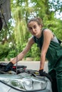 female mechanic in uniform trying to repair auto which broke down Royalty Free Stock Photo
