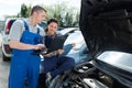 Female mechanic working on car engine with colleague Royalty Free Stock Photo