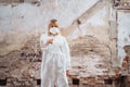 Female medic in a protective suit and medical mask standing on the ruins of a house that was bombed. She pointing finger at the Royalty Free Stock Photo