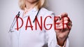 Female medic writing word DANGER on imaginary screen against white background, closeup