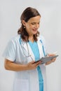 Female medical doctor wearing white medical gown with stethoscope holding clip board Royalty Free Stock Photo