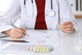 Female medicine doctor fills up prescription form to patient closeup. Panacea and life save, prescribe treatment, lega Royalty Free Stock Photo