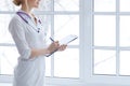 Female medicine doctor hand holding pen writing something on clipboard closeup. Royalty Free Stock Photo