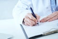 Female medicine doctor hand holding silver pen writing something on clipboard closeup. Lot of paper work in medicine Royalty Free Stock Photo