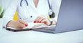 Female medicine doctor hand holding silver pen writing something on clipboard and working laptop closeup. Physician Royalty Free Stock Photo