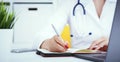 Female medicine doctor hand holding silver pen writing something on clipboard and working laptop closeup. Physician Royalty Free Stock Photo