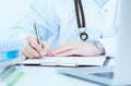 Young female medicine doctor hand holding silver pen writing something on clipboard closeup. Royalty Free Stock Photo